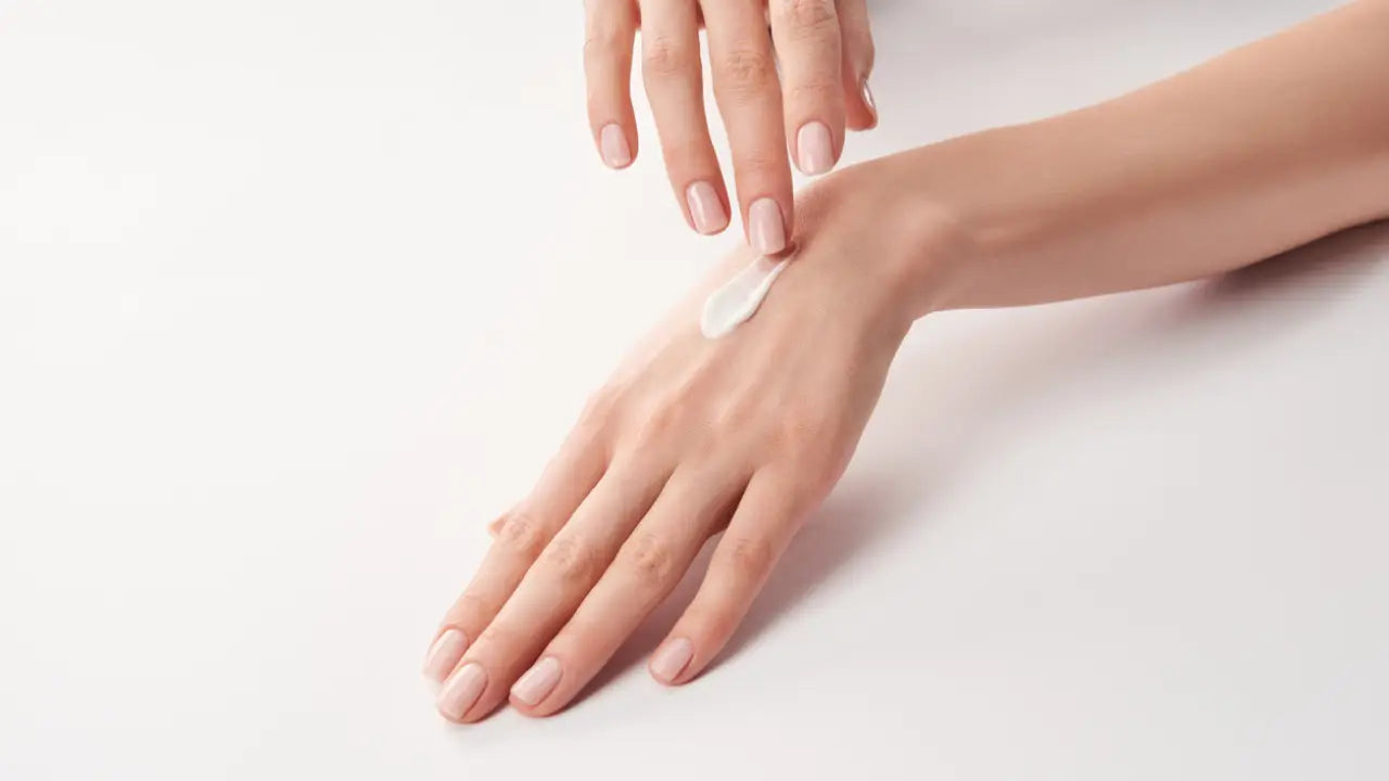 Een dot romige witte lotion op de achterkant van een hand voor perfecte nagelverzorging en hydratatie