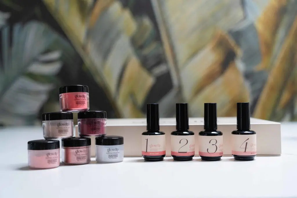Set van vier roze en zwarte gel nagellak flessen met genummerde labels naast bijpassende poeder potjes voor nagelverzorging