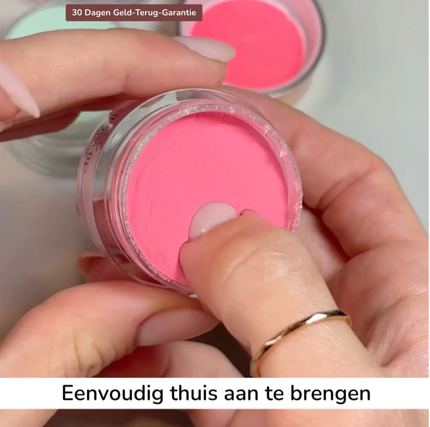 Een helder glazen potje met levendige roze dip poeder en zilveren rand voor thuis manicures