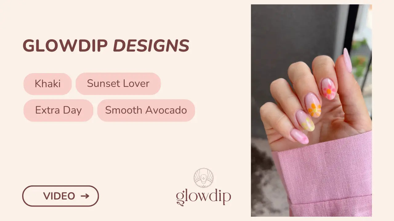 Een hand met lang, amandelvormige nagels in zachte roze tint met delicate oranje-gele bloemmotieven bij betoverde tuin