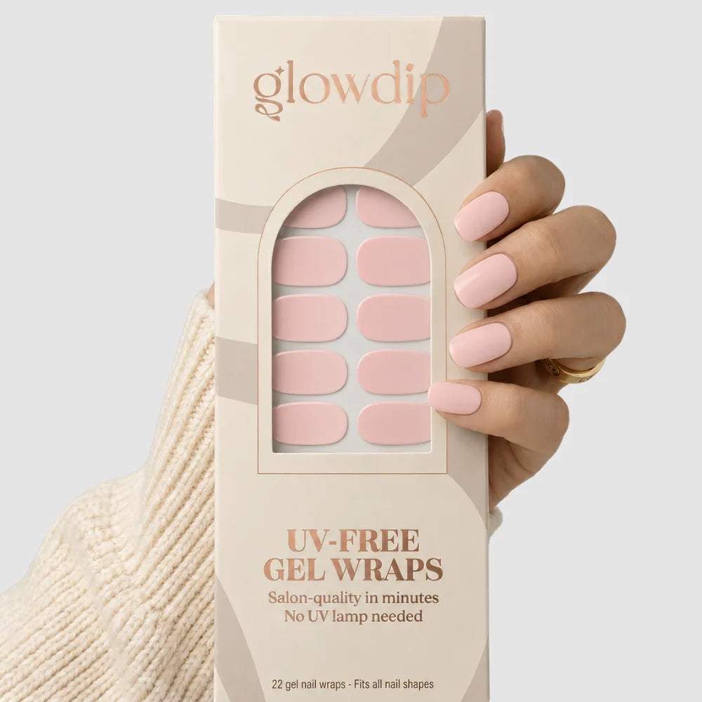 Een hand houdt een Baby Bloom uv-vrije gel nagelwrap doos met zachtroze salonkwaliteit ontwerpen zonder uv-lamp nodig