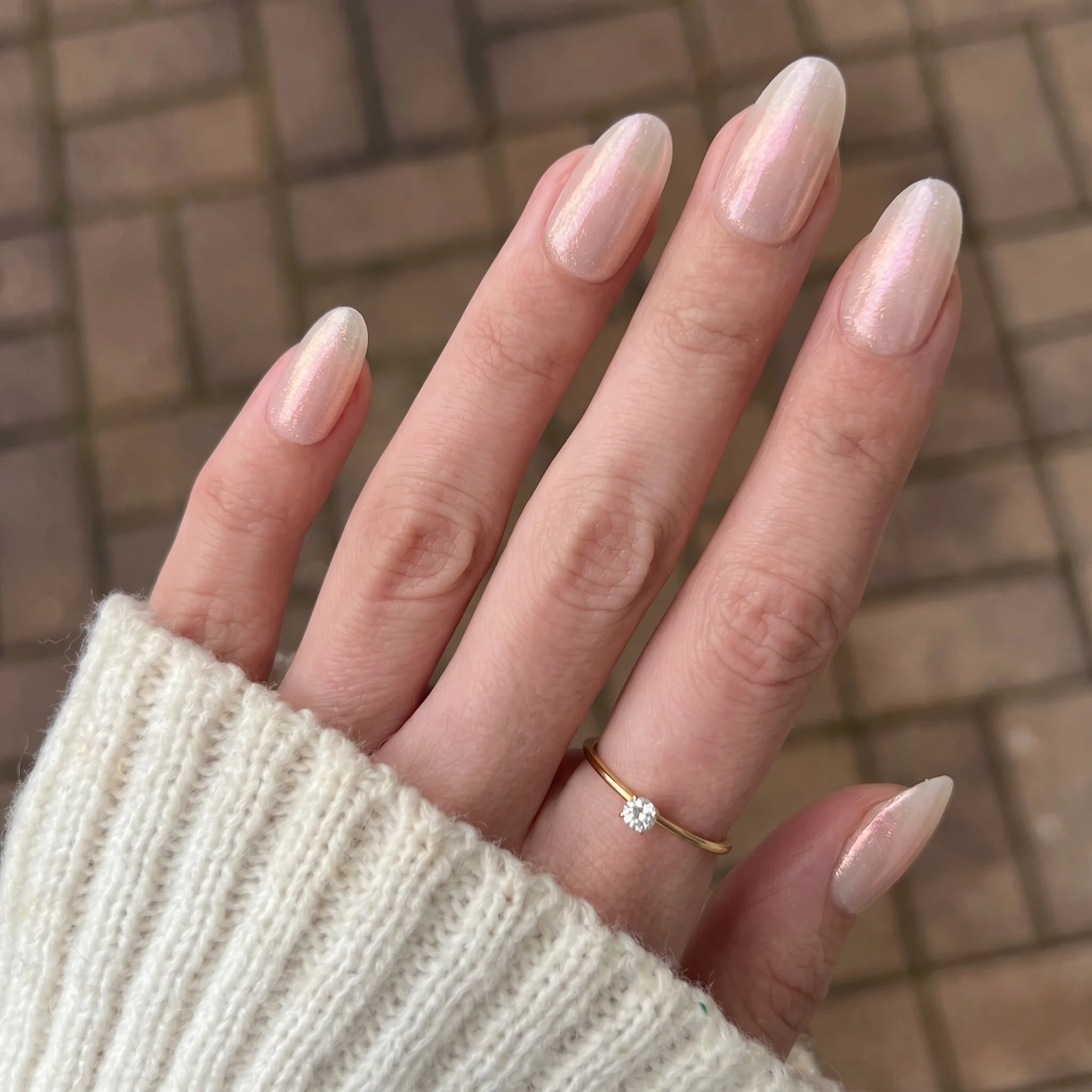 Een delicate gouden ring met een enkele fonkelende diamant in het midden bij Crimson Shift Chrome Powder