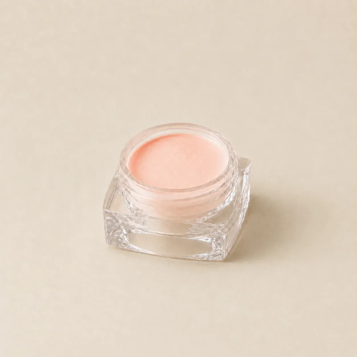 Een helder glazen vierkante pot met zacht perzikkleurige balsem uit de chrome powder bundle 5 kleuren