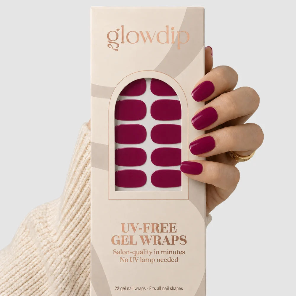 Een hand houdt een doos glow dip uv-free gel nagelwraps in diep bordeaux met 22 voorgevormde wraps
